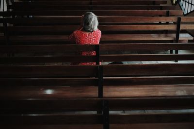 Rear view of woman sitting on pew at church