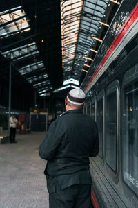 Rear view of man standing at railroad station