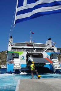 Man standing by boat against blue sky