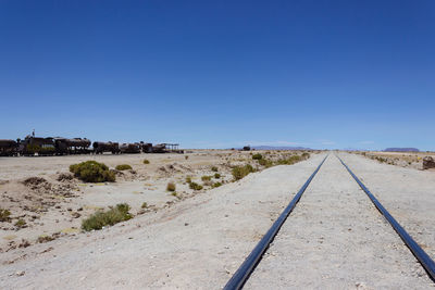 View of railroad track against clear blue sky