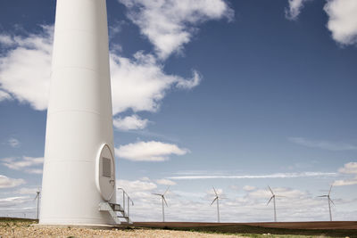 Wind turbines on field against blue sky