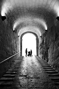 Mother and boy with baby carriage standing at archway of tunnel