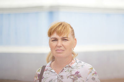 Portrait of young woman standing against wall