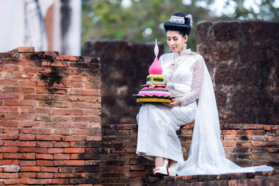 Young woman standing against brick wall