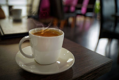 Hot indian spiced milk tea in a white mug or cup with steam cloud coming out, aka kadak masala chai