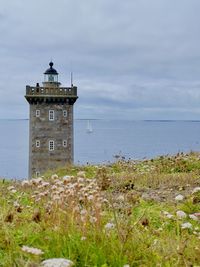 Lighthouse by sea against sky