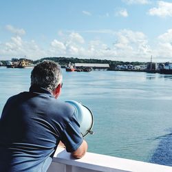 Rear view of man looking at sea against sky