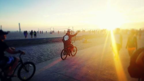 Man riding bicycle against sky during sunset