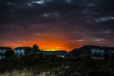 Houses and buildings against sky during sunset