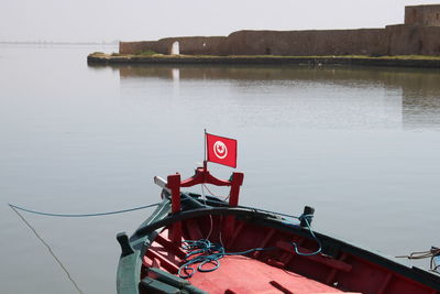 Boat moored by lake against sky