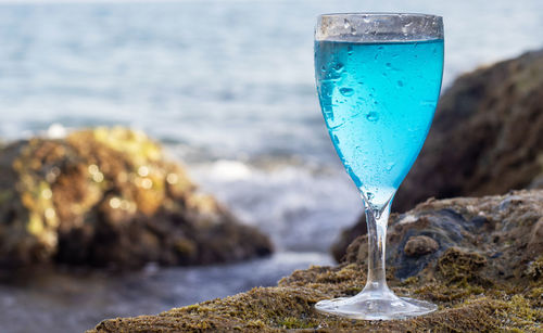 Blue lagoon cocktail on seashore big rock sands shells on sands background summer vacation mockup