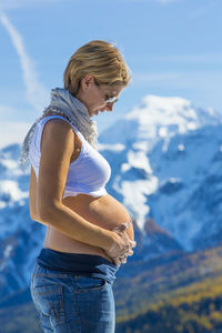 Side view of pregnant woman with hands on stomach