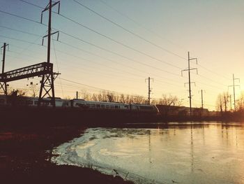 Power lines against sky at sunset