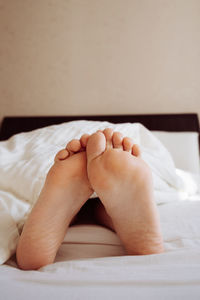 Low section of woman lying on bed at home