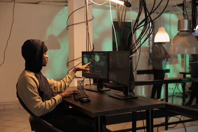 Rear view of woman using laptop at home