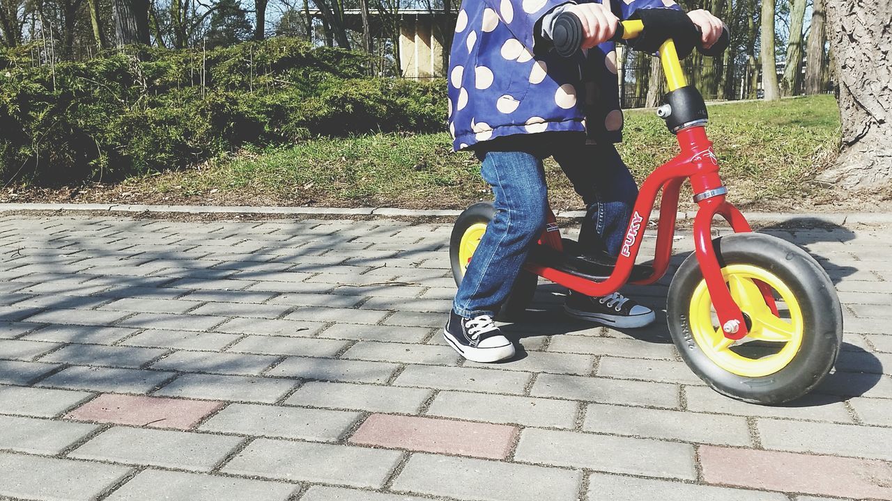 low section, lifestyles, casual clothing, leisure activity, street, person, footpath, full length, bicycle, childhood, sidewalk, walking, shoe, standing, cobblestone, men, outdoors