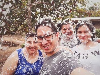 Portrait of smiling friends with party spray standing outdoors