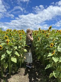 Rear view of girl standing by sunflower 