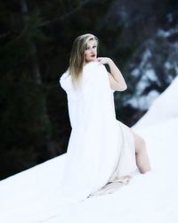 Portrait of beautiful woman wearing scarf while standing snow covered hill