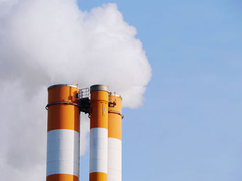 Low angle view of smoke stacks against sky