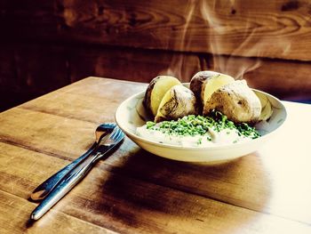 Close-up of prepared potatoes served in bowl on wooden table