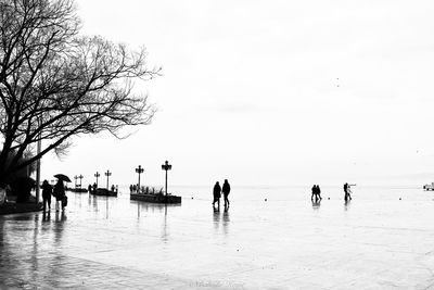 People on beach against clear sky