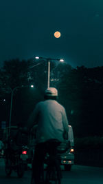 Rear view of man riding motorcycle on road at night