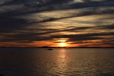 Scenic view of sea against cloudy sky during sunset