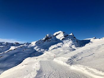 Scenic view of snowcapped mountains against clear blue sky