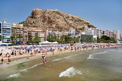 People enjoying at beach against mountain