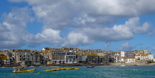 View of buildings by sea against cloudy sky