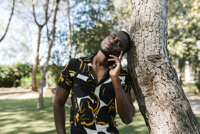 Portrait of young man holding tree trunk