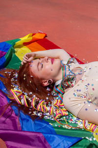 Young woman lying down on rainbow flag