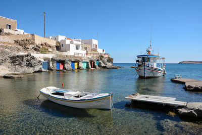 Boats moored on sea against clear blue sky