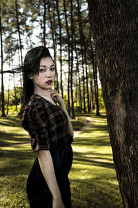 Portrait of woman standing on tree trunk