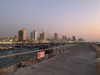 City by river and buildings against clear sky