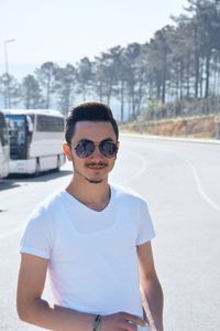 Portrait of young man wearing sunglasses standing on road