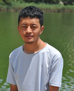 A young guy looking at camera and standing beside of lake with copy space 