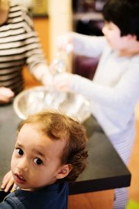 High angle portrait of baby boy with siblings around table at home