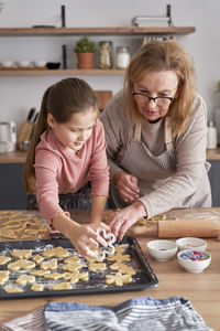 Grandma and granddaughter rolling dough