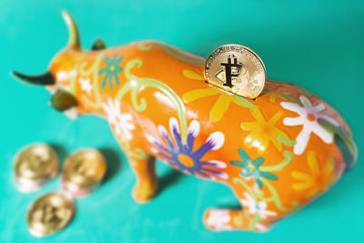 Close-up of bitcoin in piggy bank against blue background