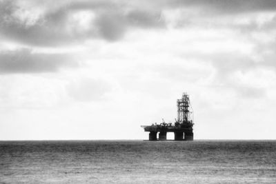 Scenic view of sea with drilling rig against sky