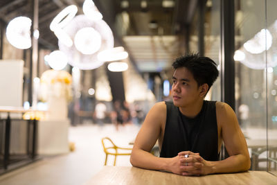 Portrait of man sitting in illuminated restaurant