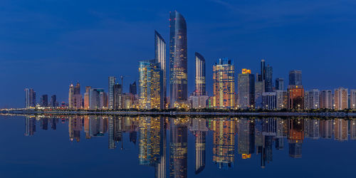 Reflection of illuminated buildings in lake against sky