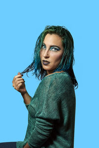 Portrait of woman standing against blue background