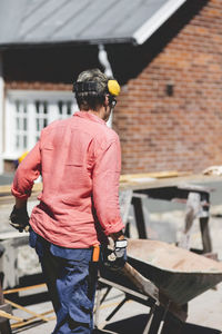 Rear view of senior woman pushing wheelbarrow at yard