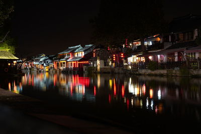 Illuminated buildings by river at night