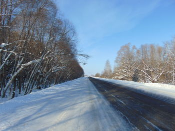Road amidst trees against sky during winter