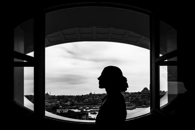 Side view of silhouette woman looking through window