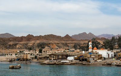 Boats in sea by buildings against sky